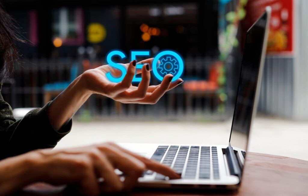 Person holding SEO icon while using a laptop, showing modern SEO strategies